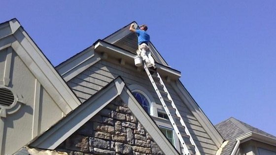Hand-brushing paint on a stone gable peak