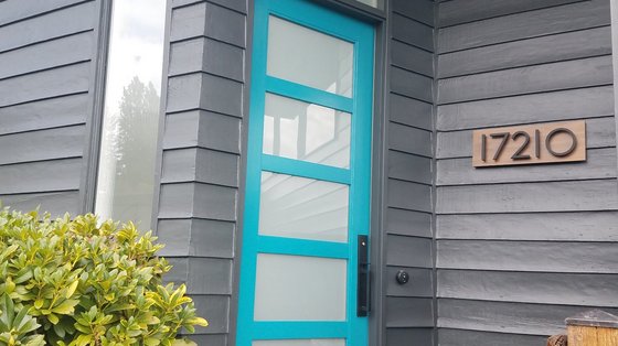 Charcoal siding with a bold turquoise entry door