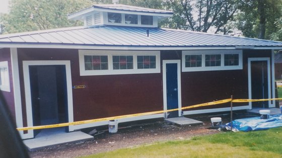 Burgundy outbuilding with white trim and metal roof