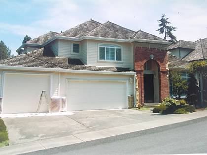 Cream home with brick entry arch, windows masked during painting