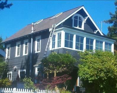 Older home painted dark blue with fresh white window trim behind a picket fence